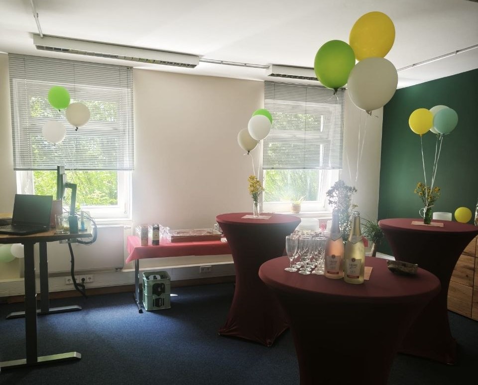 Büro mit Stehtischen, gedeckt mit Prosecco zum Anstoßen und bunten Luftballons